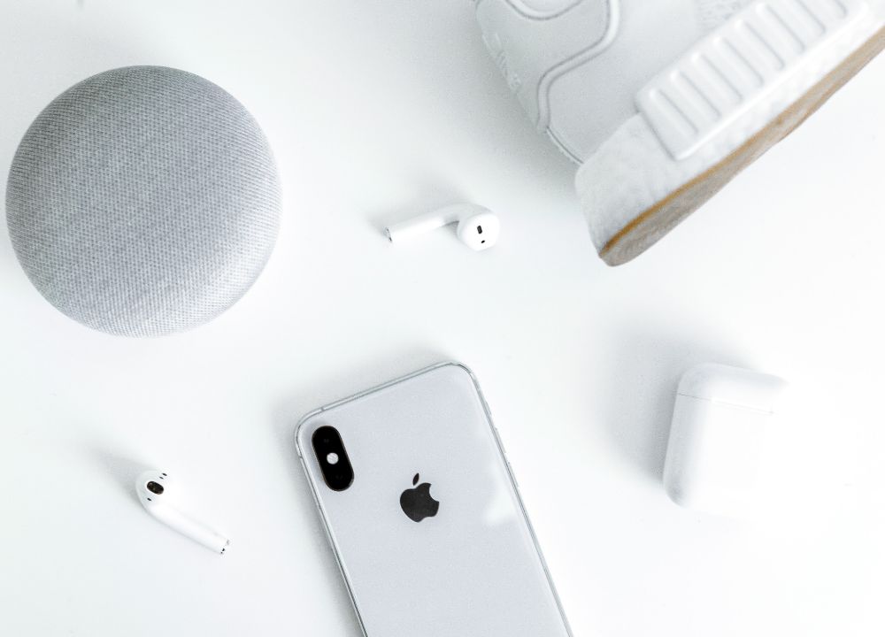 Trainer, headphones, speaker, phone and plant on table