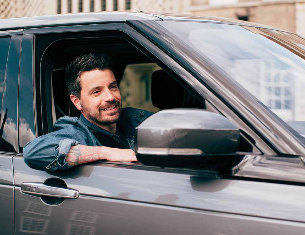 Man sat in the driver's seat of a 4x4 smiling