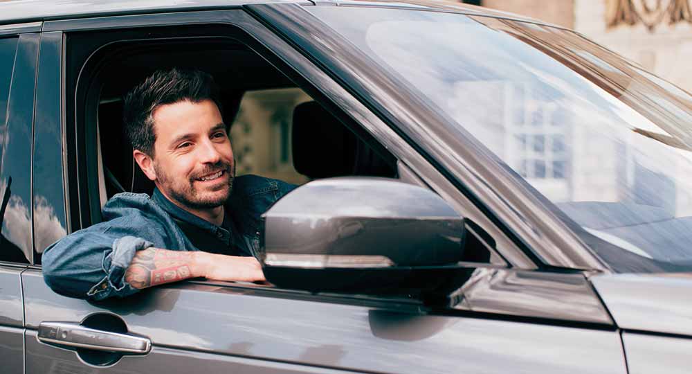 Man sat in the driver's seat of a 4x4 smiling