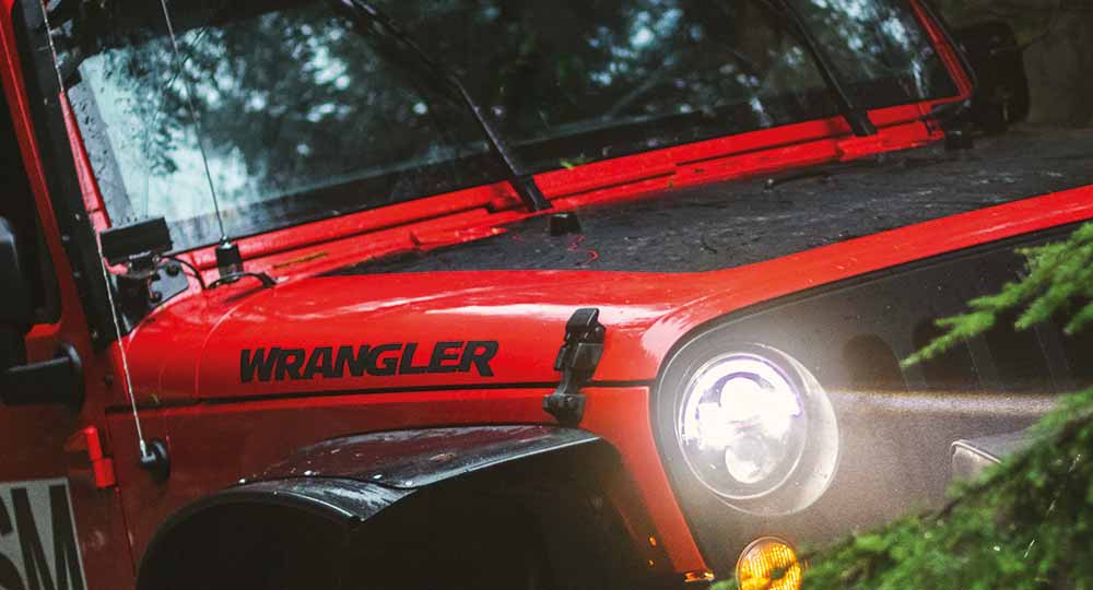 Jeep Wrangler off-roading with headlights on