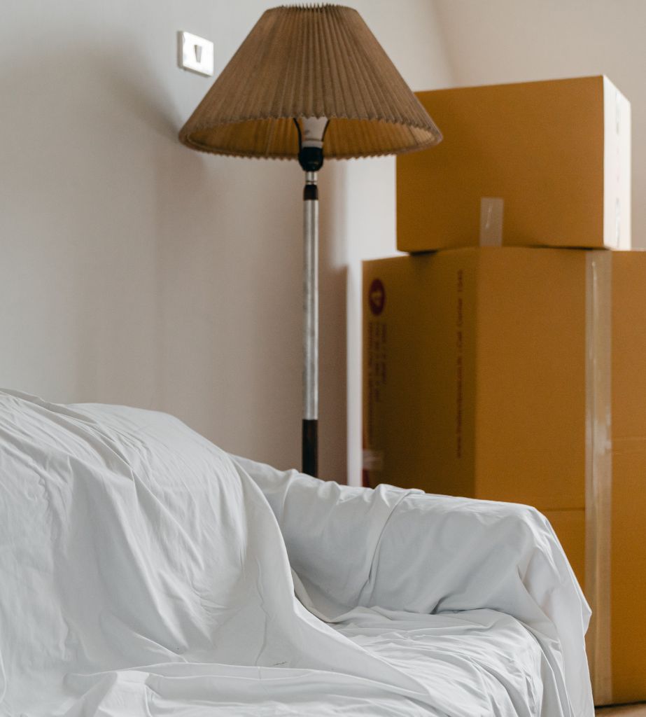 Unoccupied property pictured with protective sheet on sofa and boxes in background