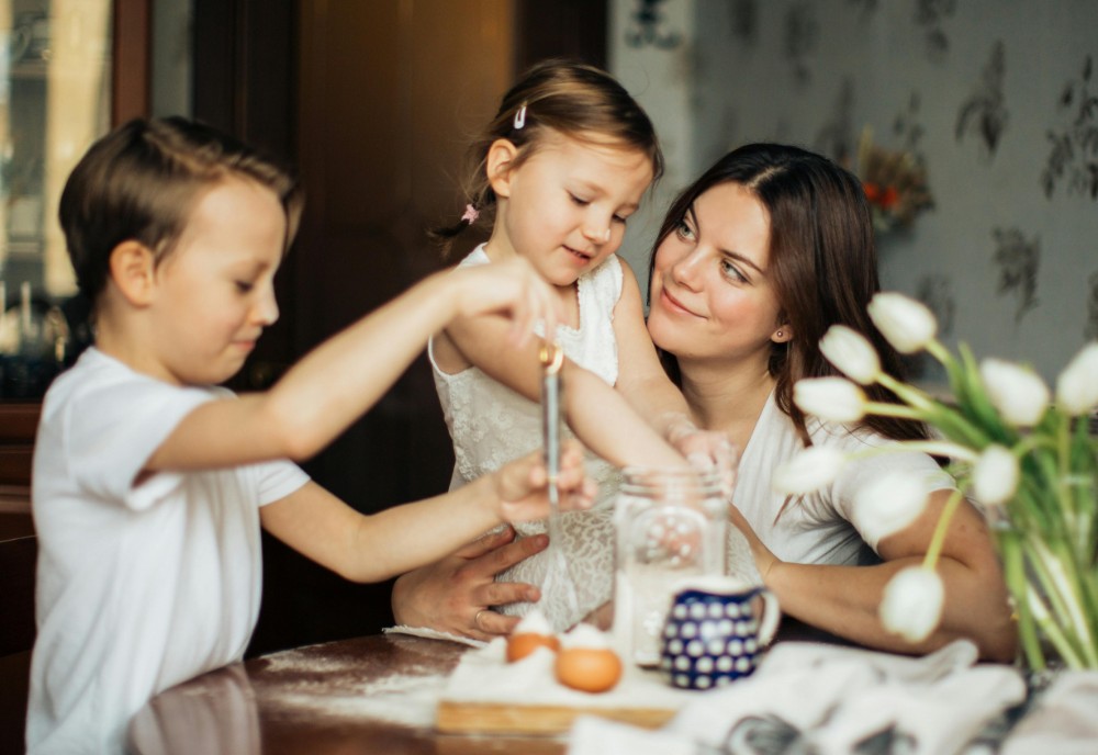 Mum with two young daughters baking at the kitchen table