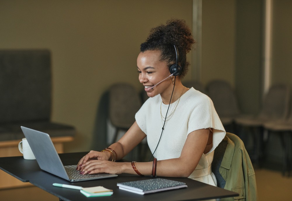 Happy young female working from home for an insurance company with headset and laptop 