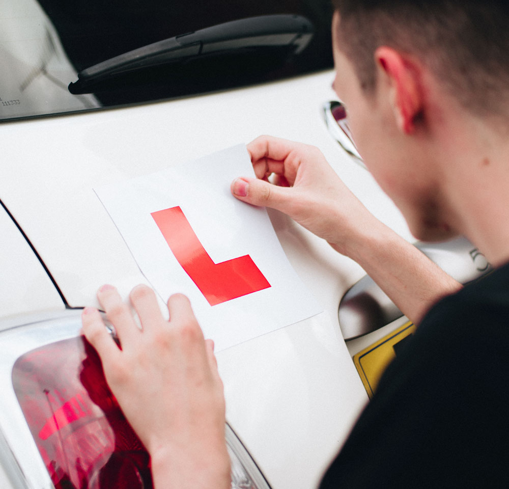Man putting L plate on car