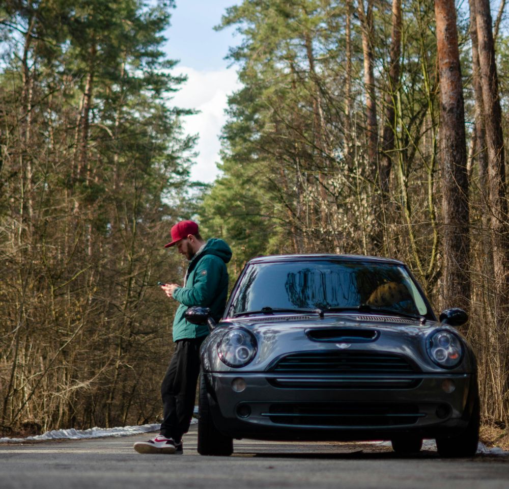 Young man standing beside black mini cooper