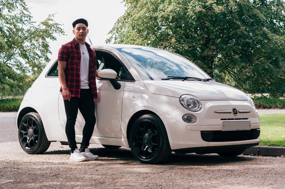Young person standing next to car