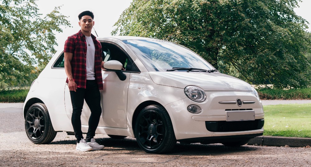 Young person standing next to car