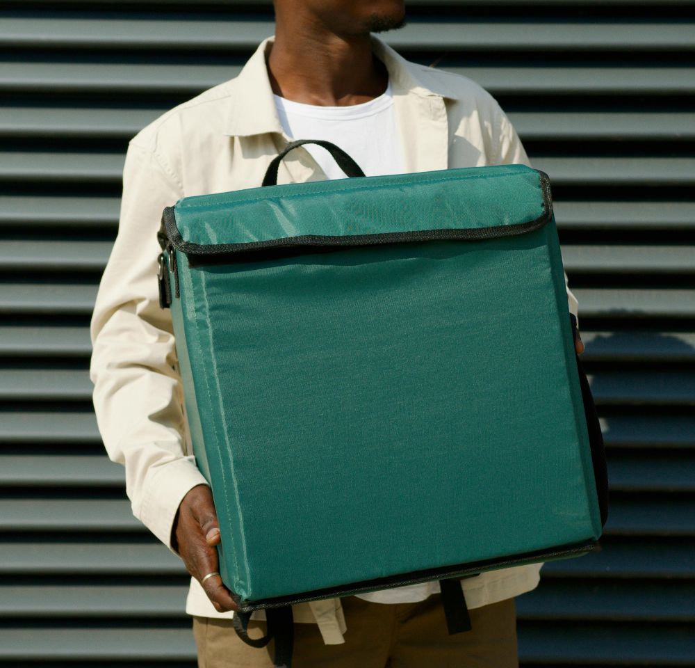 Courier holding green cool bag