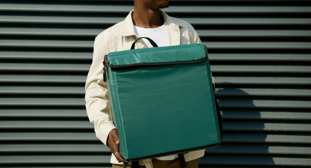 Courier holding green cool bag