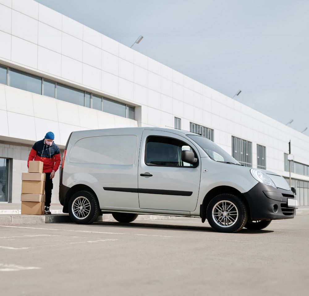 Courier driver unloading boxes from a silver van