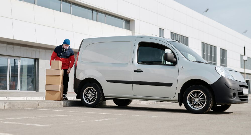 Courier driver unloading boxes from a silver van