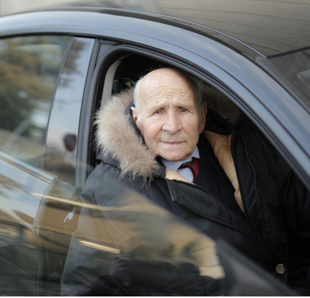 Smartly dressed older man sitting in passenger side of black car