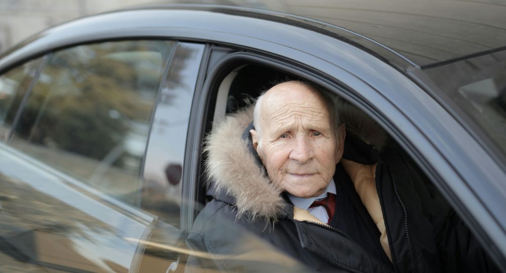 Smartly dressed older man sitting in passenger side of black car
