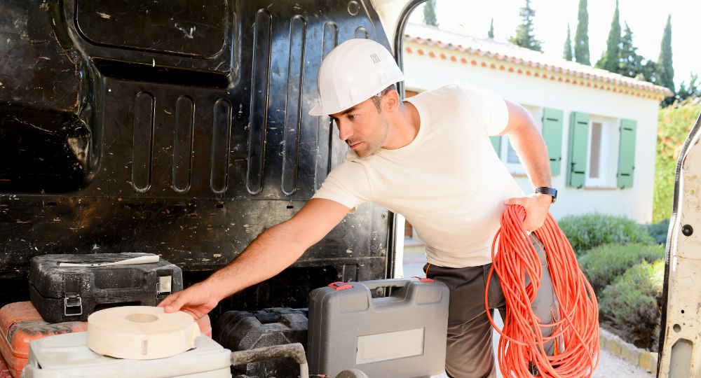 Building wearing a hard hat reaching in van to get tools
