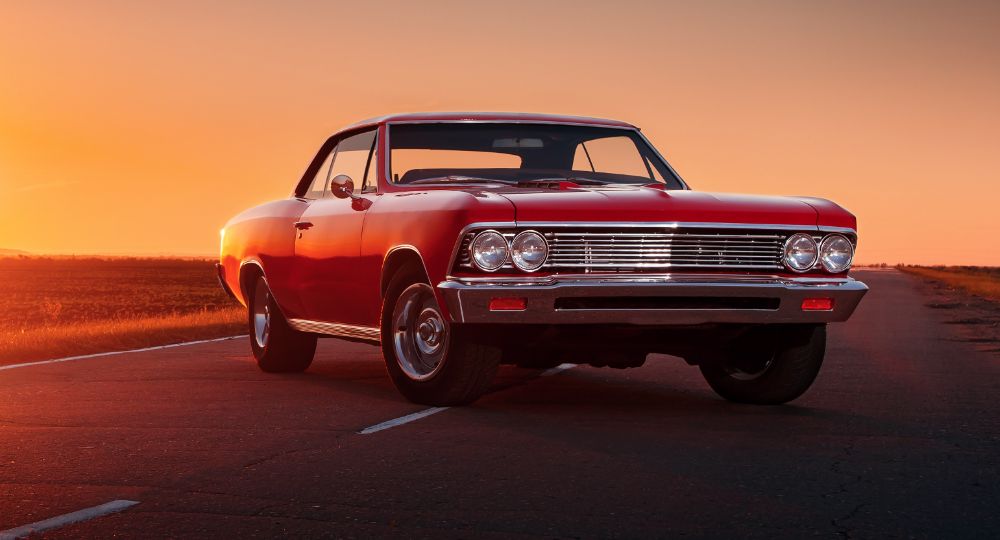 Red American muscle car with sun setting in the background