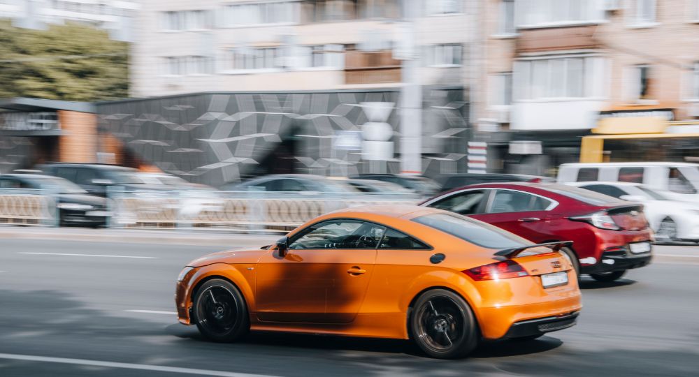 Orange Audi TT driving down the road