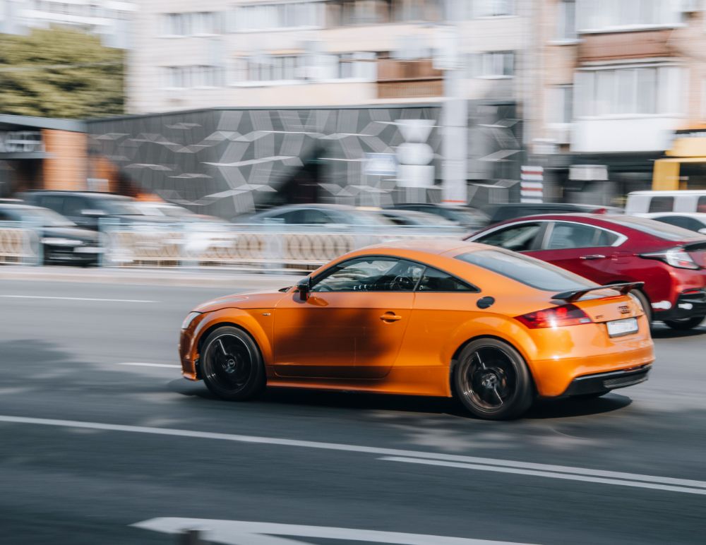 Orange Audi TT driving down the road