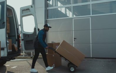 Person walking with delivery boxes from his van to the house