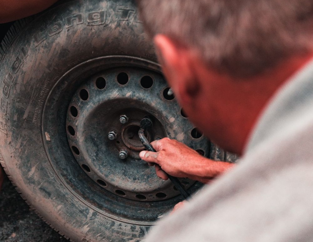 Middle aged man removing wheel from tyre 