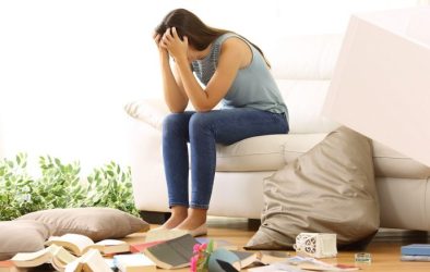 Woman sitting on sofa with head in her hands as she's been burgled