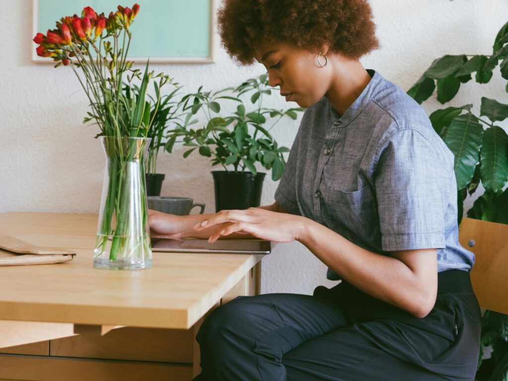 Woman sat at kitchen table concentrating and working on tablet