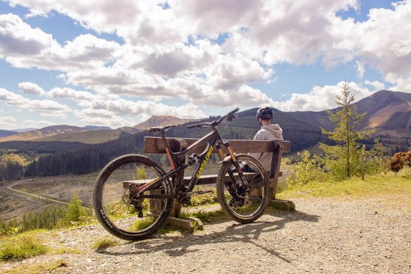 Person sat on a bench enjoying the view with bike next to him