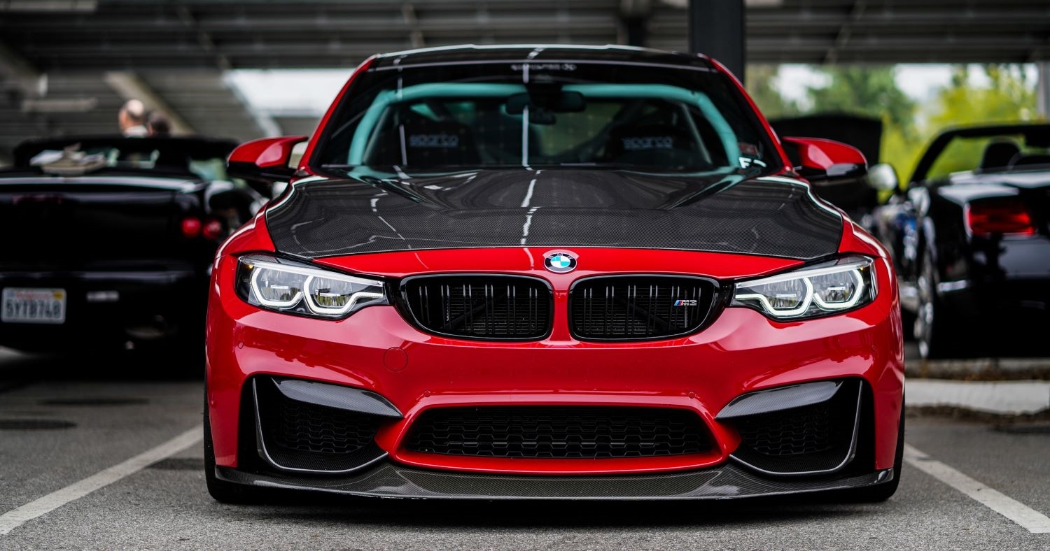 Modified red and black BMW parked in a car park outside