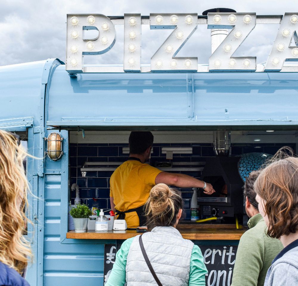 People standing in front of a pizza truck