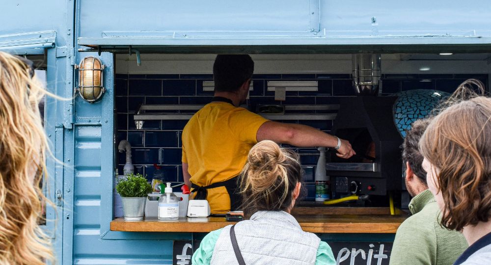 People standing in front of a pizza truck