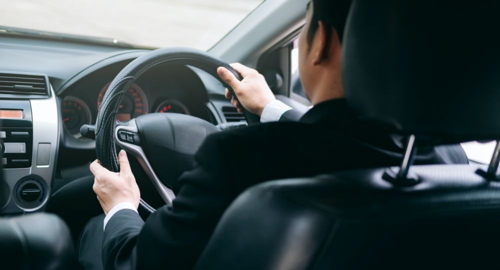 Man in a suit driving a car