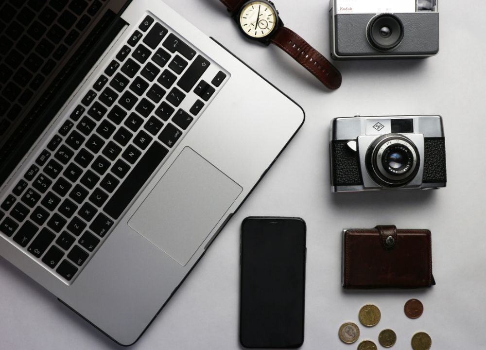 Laptop, phone, camera, watch and wallet on desk
