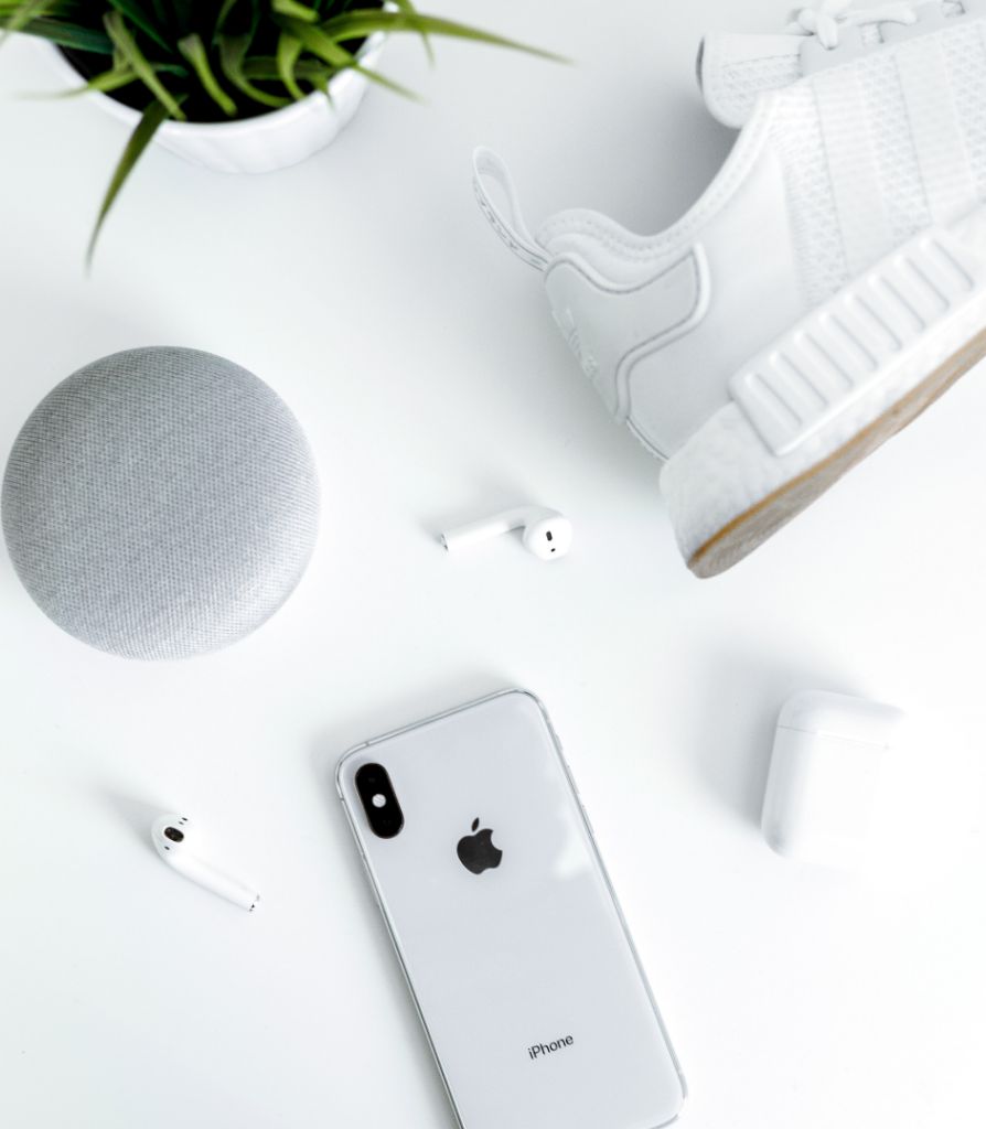 Trainer, headphones, speaker, phone and plant on table