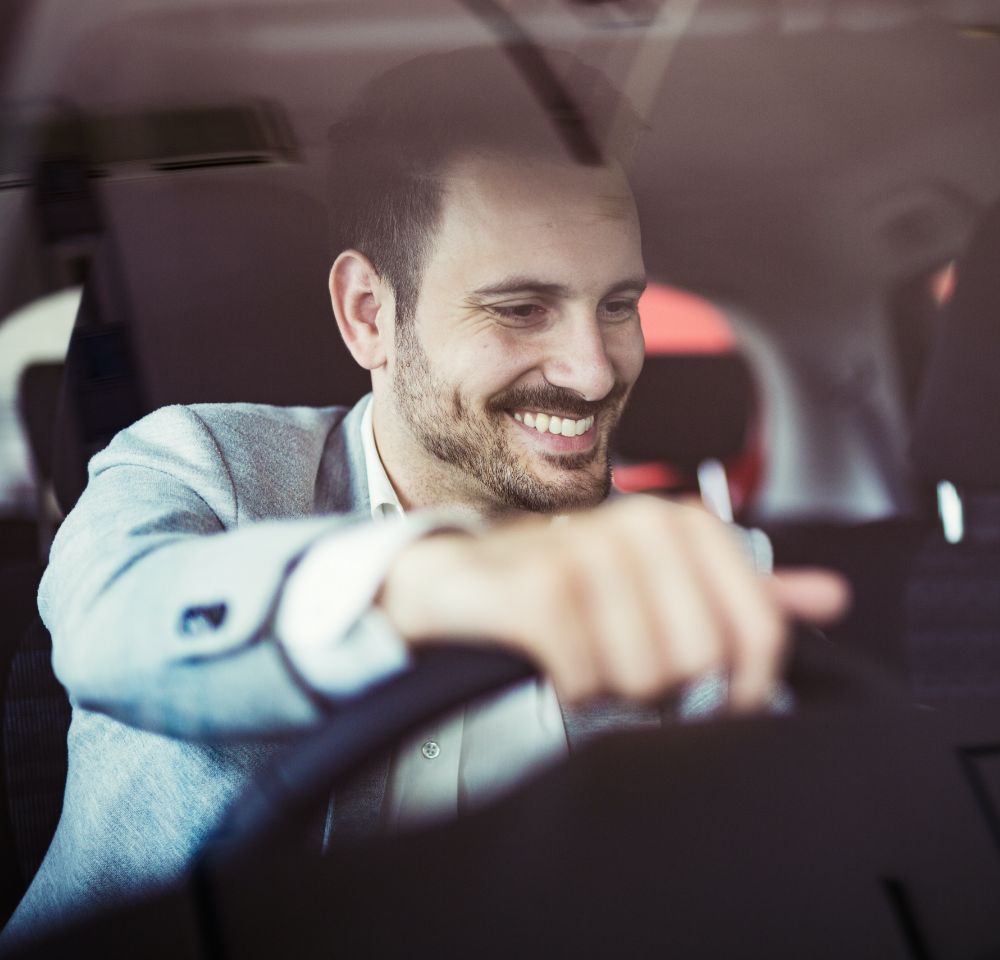 Person smiling with hand on steering wheel