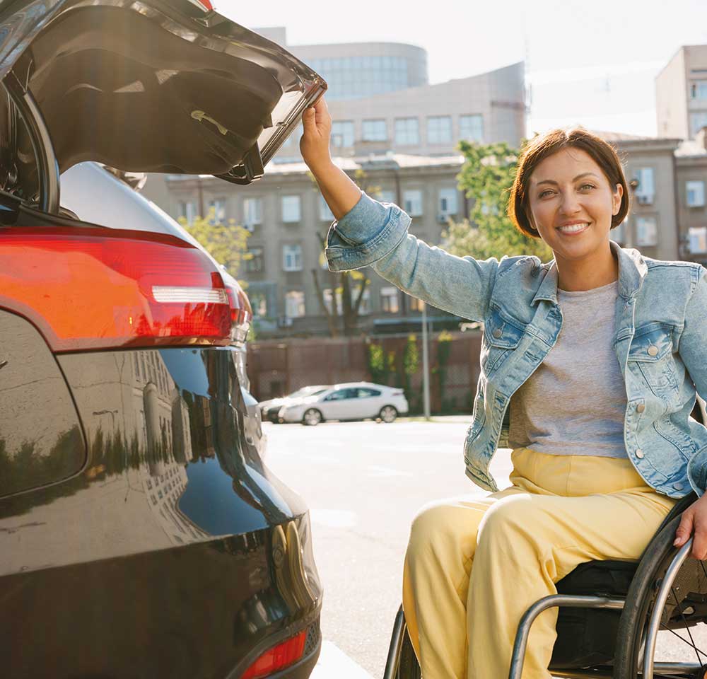 Person in wheelchair smiling into camera and holding her car boot