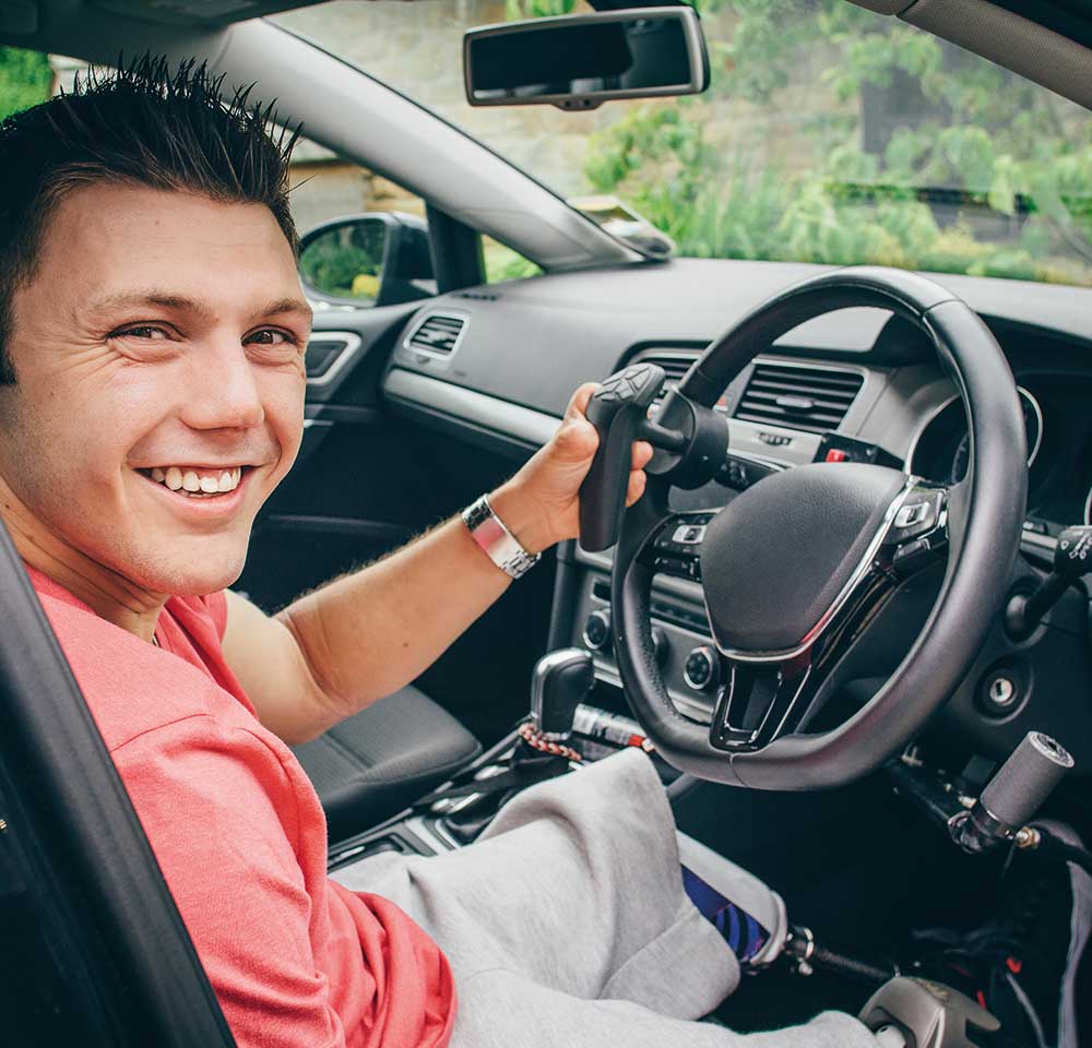 Disabled driver sitting in the driver's seat of an adapted vehicle