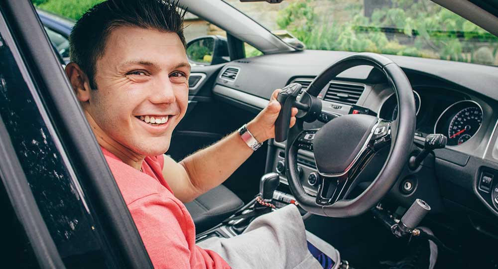 Disabled driver sitting in the driver's seat of an adapted vehicle