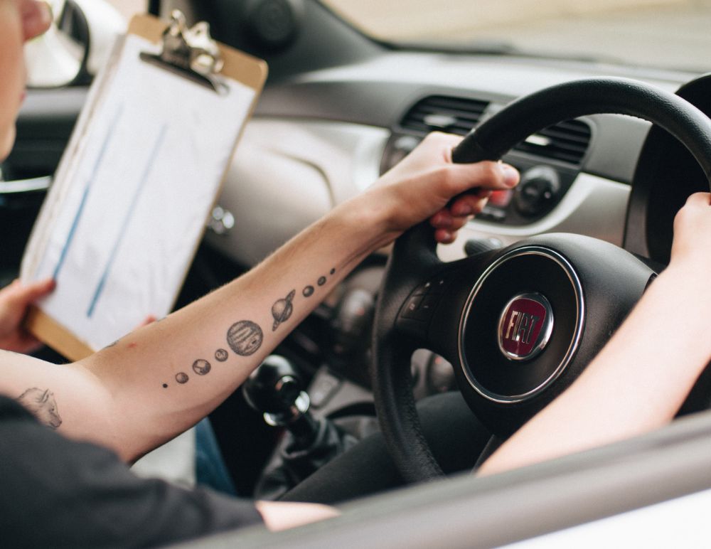 learner driver holding a stearing wheel of a fiat 500 during a lesson