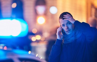 Person near police car holding head in hands