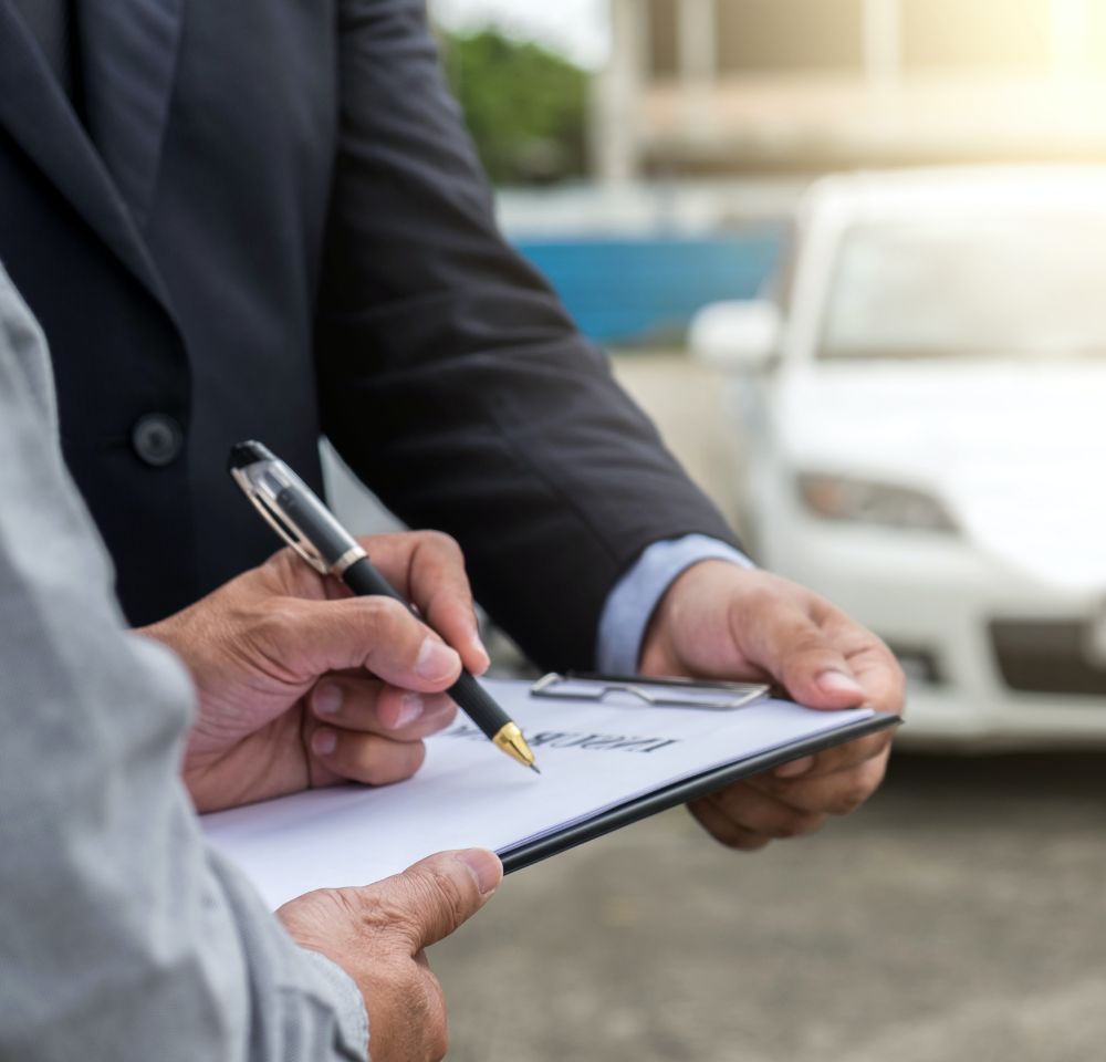 People signing document in front of car