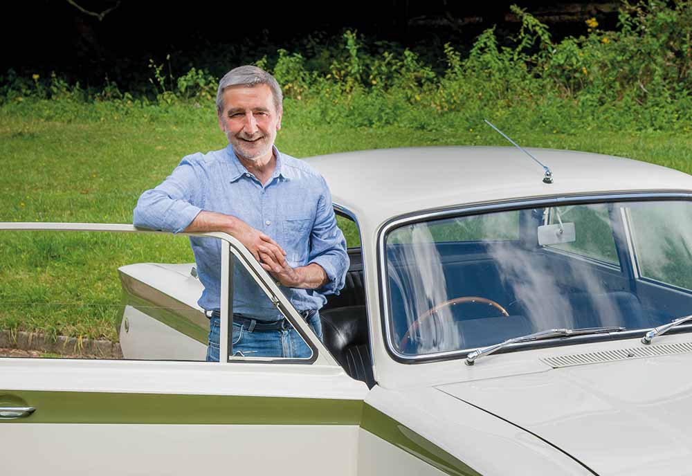 Man standing next to his Ford Cortina smiling with grass in the background