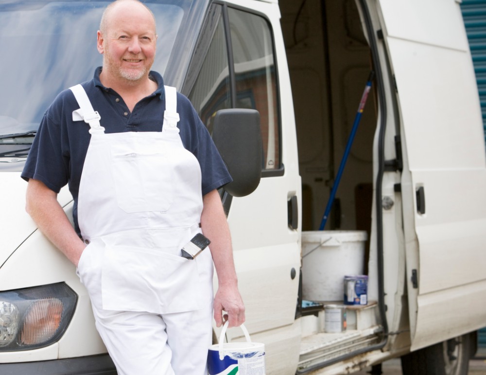 Decorator standing outside his van with painting equipment showing through the open side door