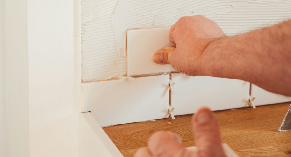 man putting up wall tiles