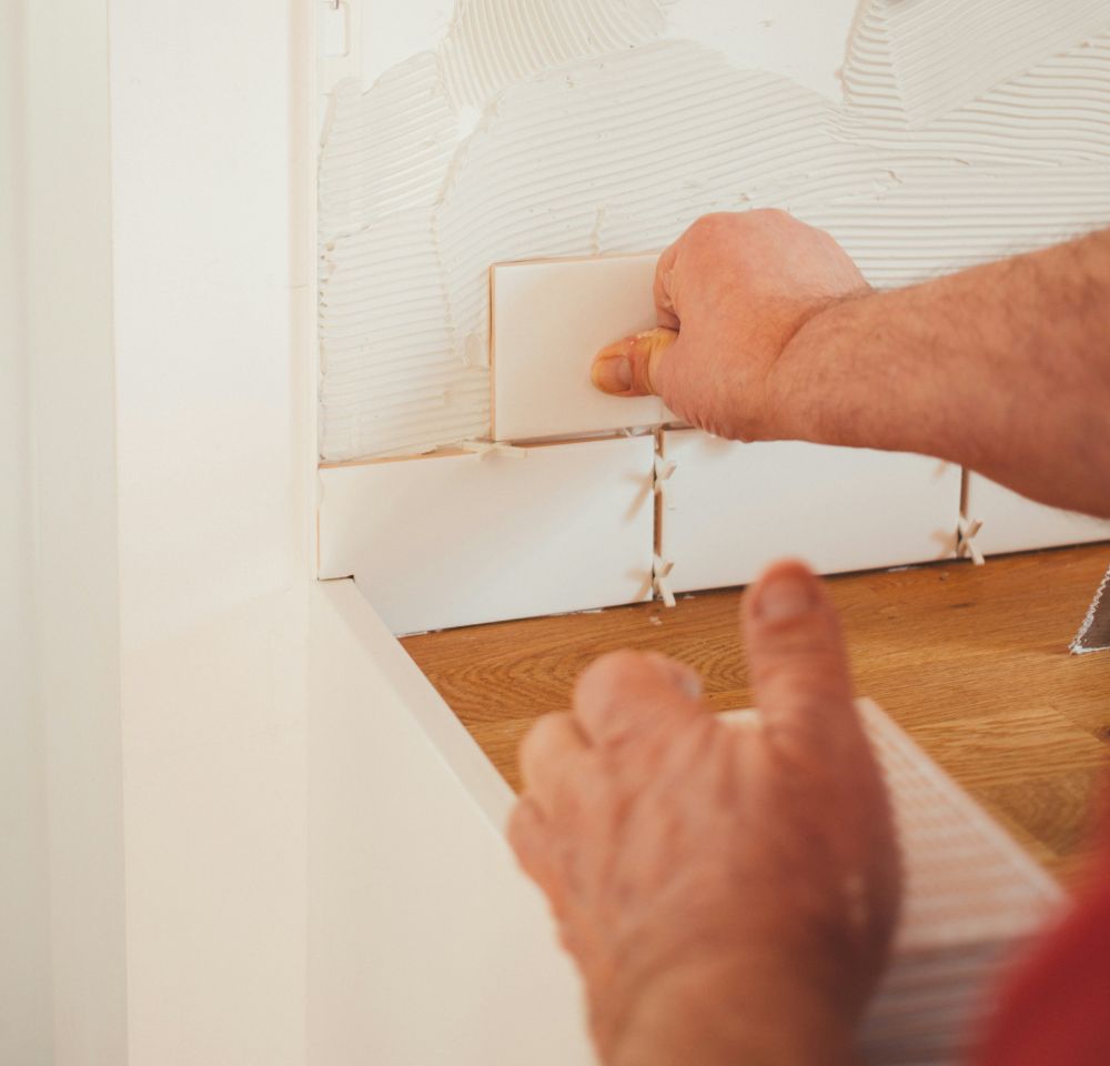 man putting up wall tiles