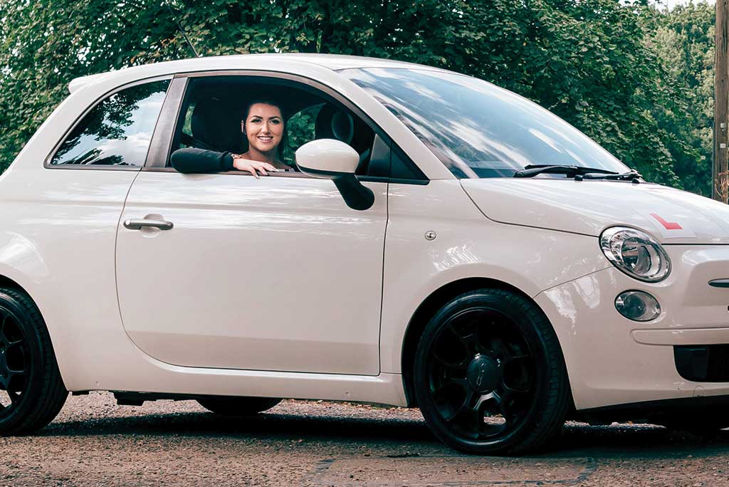 Young learner driver smiling from the driver's seat