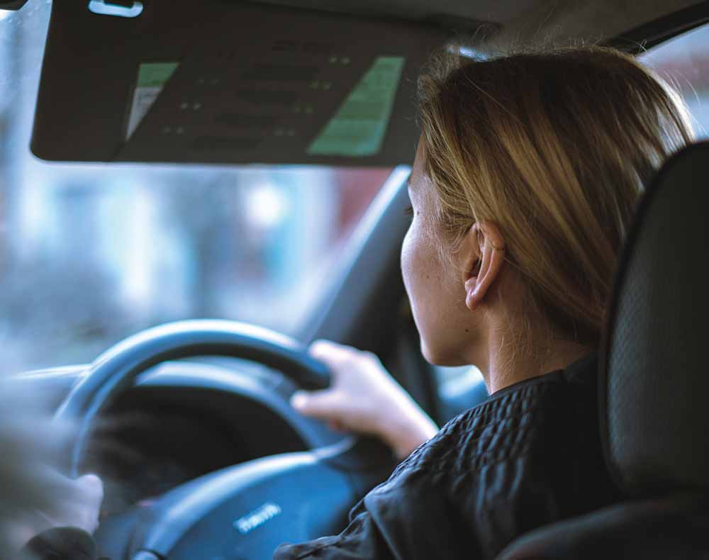 Woman sitting in car with two hands on wheel