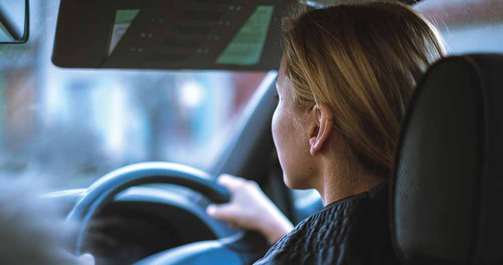 Woman sitting in car with two hands on wheel