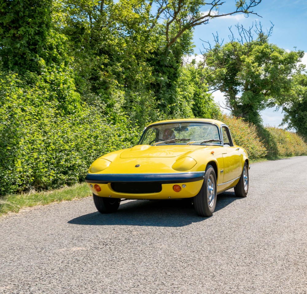 Yellow classic car driving down the road