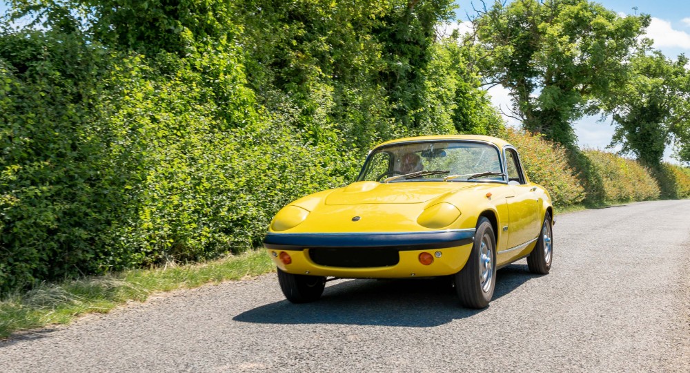 Yellow classic car driving down the road