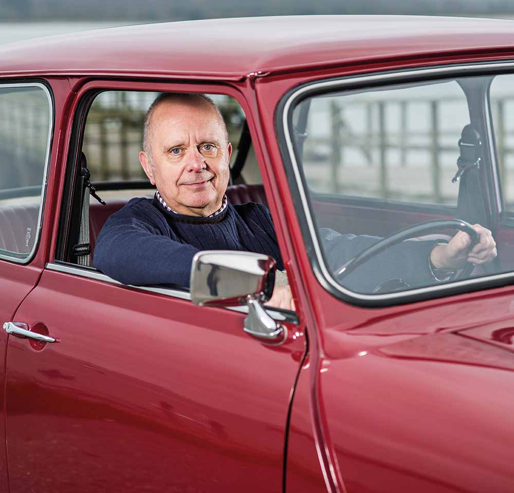 Man holding onto the steering wheel of a red Mini