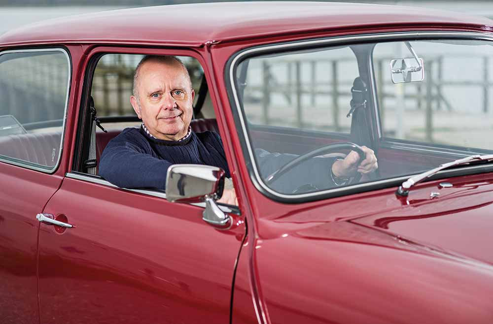 Man holding onto the steering wheel of a red Mini